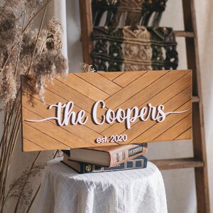 May include: A wooden sign with a chevron pattern and the text "The Coopers est. 2020" in white lettering.