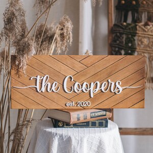 May include: A wooden sign with a chevron pattern and the text "The Coopers est. 2020" in white lettering.