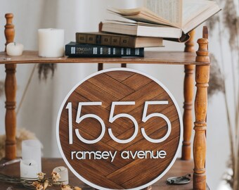 Letrero de dirección redondo blanco, placa con número de casa y nombre de calle.