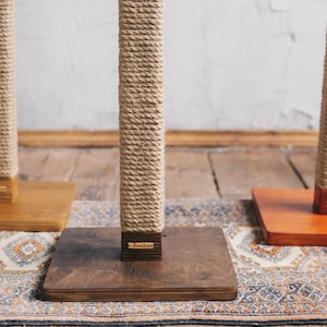 Puede incluir: Tres postes para rascar para gatos de cuerda de sisal natural con bases de madera. Las bases están teñidas en diferentes colores: marrón, naranja y marrón oscuro.