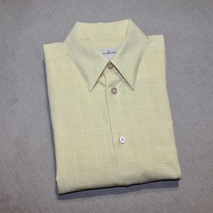 May include: A yellow and white checkered button-down shirt with a collar and a button closure.