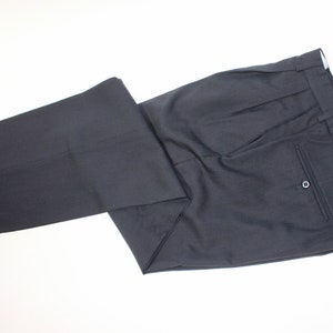 May include: A pair of dark gray pleated pants with a single back pocket.