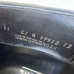 May include: Close-up of a black leather shoe sole with the text "C/R 19912 12 MADE IN THE USA OF IMPORTED LEATHERS 402N"