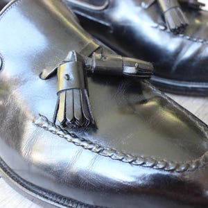 May include: A pair of black leather tassel loafers with a braided trim around the toe. The loafers have a classic design and are made of high-quality leather.