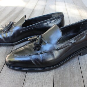May include: A pair of black leather tassel loafers. The loafers have a pointed toe and a slip-on design.