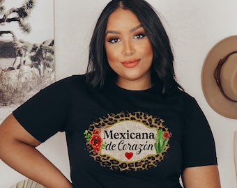 May include: Black t-shirt featuring a leopard print design and the text "Mexicana de Corazón" with a red heart. The design also includes flowers and a cactus.