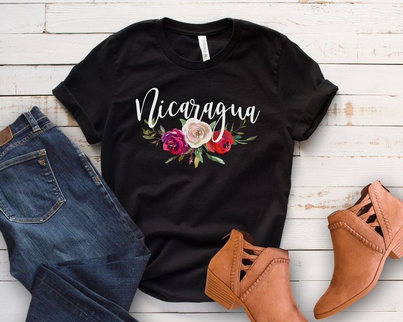 May include: Black t-shirt with white text that says "Nicaragua" and a floral design with red, white, and pink flowers.