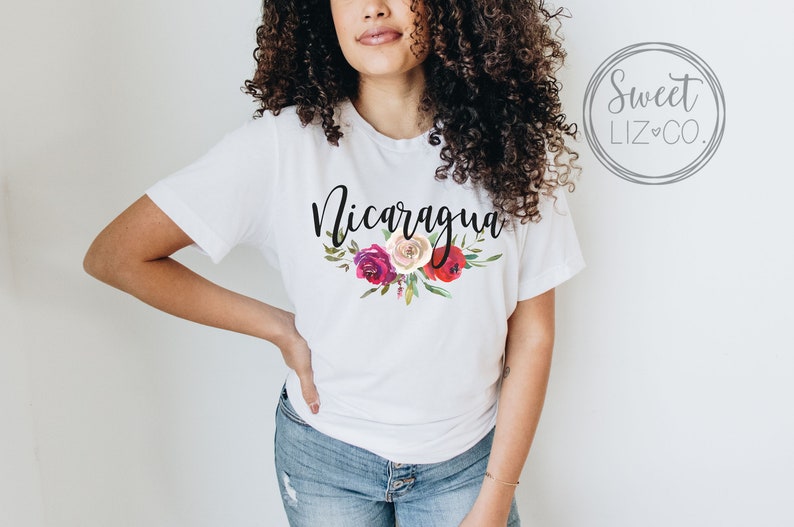 May include: White t-shirt with the word "Nicaragua" in black script and a floral design with red, pink, and white flowers.