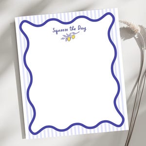 May include: A white notepad with a blue wavy border and vertical striped background. The text "Squeeze the Day" is written in cursive, with a small illustration of lemons and leaves.