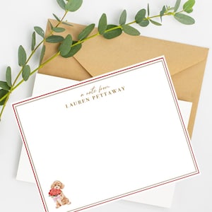 May include: A white card with a red and gray border. The card has the text "a note from LAUREN PETTAWAY" in gold lettering. A watercolor illustration of a brown poodle holding a bouquet of pink flowers is at the bottom of the card.