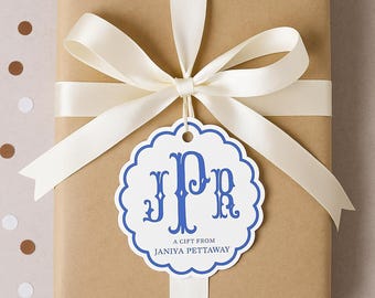 May include: A brown gift box with a white satin ribbon tied in a bow. A white gift tag with blue scalloped edges and blue lettering is attached to the ribbon. The tag says "JPR" in a decorative font and "A gift from JANIYA PETTAWAY".