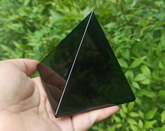 Könnte beinhalten: Ein schwarzer Obsidian-Pyramidenkristall, eine glatte, polierte, geometrische Form.