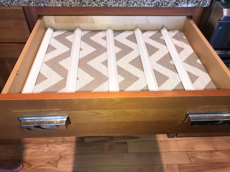 May include: A wooden drawer with a white and gray chevron patterned liner and white dividers. The drawer has two silver handles.