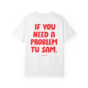 Könnte beinhalten: Ein weißes T-Shirt mit kurzen Ärmeln und einem auffälligen roten Schriftzug auf der Rückseite, der IF YOU NEED A PROBLEM TU SAM lautet. Unter dem Haupttext ist das Wort REDLINE in kleineren roten Großbuchstaben gedruckt. Rundhalsausschnitt.