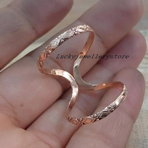 Könnte beinhalten: Ein roségoldener Ring mit einem aufwendigen Design, das ein Blumen- und geometrisches Muster aufweist. Der Ring umschließt zwei Finger, mit dem Text "Luckyjewellerystore" sichtbar.