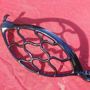May include: Black cast iron sewing machine foot pedal with a decorative, openwork design. The pedal is in good condition with a glossy black finish.