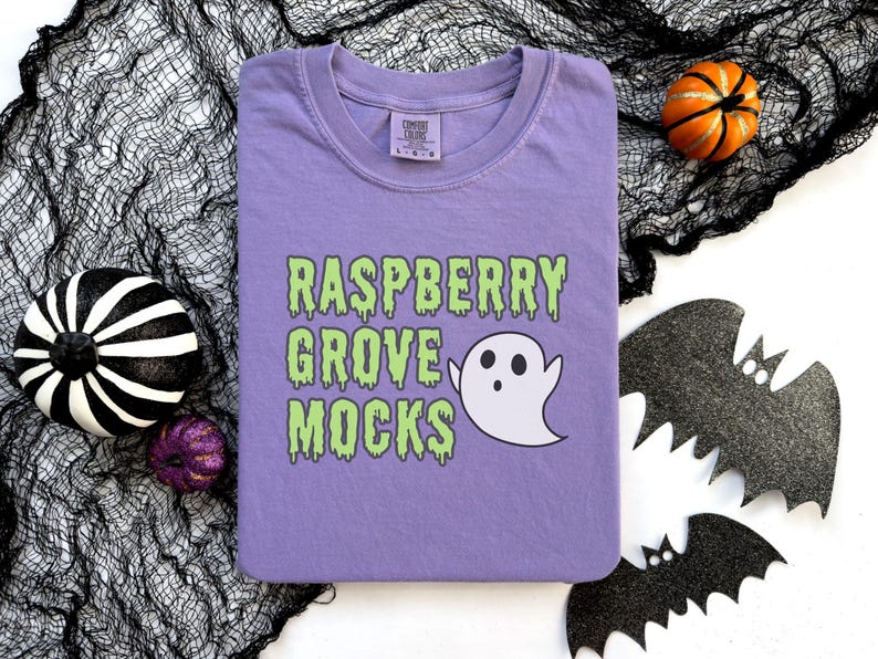 May include: A purple t-shirt with a green dripping text design that says "Raspberry Grove Mocks" and a white ghost graphic.