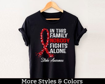Camisa de concientización sobre accidentes cerebrovasculares, en esta familia nadie lucha solo, escuadrón de apoyo contra accidentes cerebrovasculares, guerrero contra accidentes cerebrovasculares, luchador contra accidentes cerebrovasculares, camiseta de sobreviviente de accidentes cerebrovasculares