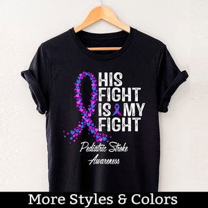 May include: Black t-shirt with a purple and blue ribbon made of hearts. The text "His Fight Is My Fight" is printed in white with a purple ribbon symbol. The text "Pediatric Stroke Awareness" is printed below the ribbon.