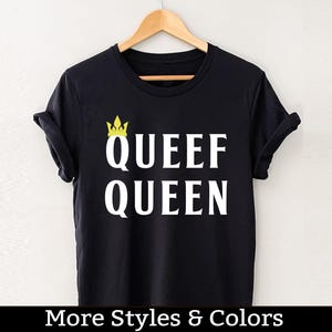 May include: Black t-shirt with white text that reads "Queef Queen" and a gold crown graphic.