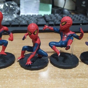 Peut inclure: Quatre figurines de Spider-Man de petite taille, rouges et bleues, avec des yeux noirs et un symbole d'araign&eacute;e blanc sur la poitrine. Chaque figurine est pos&eacute;e diff&eacute;remment et se tient sur une base noire avec un motif de toile d'araign&eacute;e.