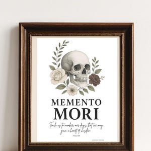 May include: A framed print with a skull and floral design. The skull is surrounded by roses and leaves. The words "MEMENTO MORI" are displayed in bold text, with a quote below. The frame is dark brown.