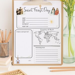 Puede incluir: Un portapapeles con una hoja de trabajo "Saint Feast Day". La hoja de trabajo incluye secciones para informaci&oacute;n, un mapa del mundo y un espacio para crear un retrato de un santo. L&aacute;pices, un portal&aacute;pices y un &aacute;baco est&aacute;n en primer plano.