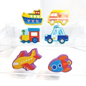 May include: Six brightly coloured wooden transport toys. The set includes a yellow aeroplane, a blue and orange rocket, a yellow and red fire engine, a blue police car, a blue and yellow boat, and a train.