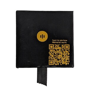 May include: Black velvet box with a gold logo and a QR code that says "Scan to see how Memorial works".