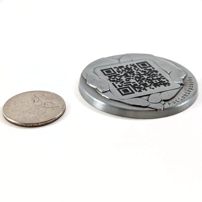 Our Channenge Coin next to a US Quarter. The coin is low-profile with 3d textures and a custom QR code stamped into the metal, with a full lifetime guarantee.