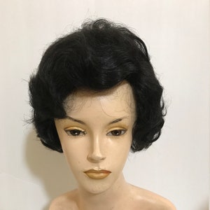 May include: A black wig with short, curled hair. The wig is styled in a vintage, 1950s look.