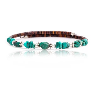 May include: A turquoise and brown beaded necklace with silver accents. The necklace is made of small, round turquoise beads and brown beads, with silver beads separating the turquoise beads.