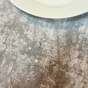 May include: A close-up of a gray and white patterned tablecloth with water droplets on the surface.
