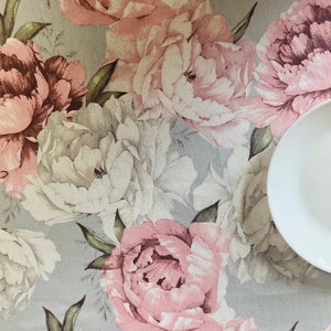 May include: A grey and white floral tablecloth with a pink and white floral pattern. The tablecloth features a variety of flowers, including peonies, roses, and lilies. The tablecloth is made from a soft, durable fabric and is perfect for any dining table.