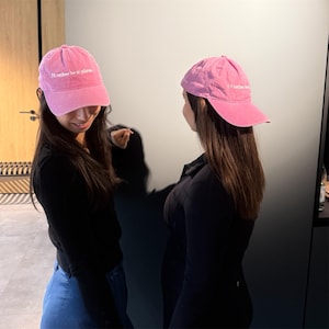 Peut inclure: Deux casquettes de baseball roses avec le texte "I'd rather be at pilates" en blanc. Les casquettes sont portées par deux personnes. Les casquettes sont de couleur rose unie.