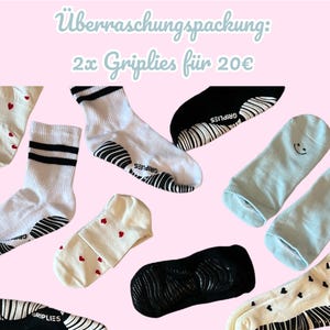 Könnte beinhalten: Verschiedene Socken in verschiedenen Stilen und Farben, darunter weiße Socken mit schwarzen Streifen, Socken mit roten Herzen und hellblaue Socken mit Smiley-Gesichtern. Die Socken sind auf rosa Hintergrund angeordnet.