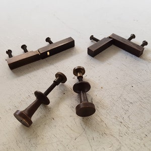 Peut inclure: Ensemble d'outils de menuiserie anciens, comprenant des serre-joints en bois et des ajusteurs à vis. Les outils sont en bois brun foncé et en laiton, disposés sur une surface claire et texturée.