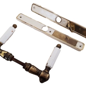 Può includere: Un set di ferramenta per porte d'epoca con maniglie in porcellana bianca e piastre in ottone. Le maniglie sono fissate a un'asta in ottone.