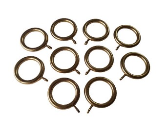 May include: Ten gold metal curtain rings with a hook on each ring.