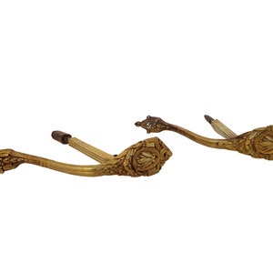 Puede incluir: Un par de soportes de pared de metal dorado adornados con intrincados diseños florales. Los soportes son curvos y tienen un remate decorativo en el extremo.