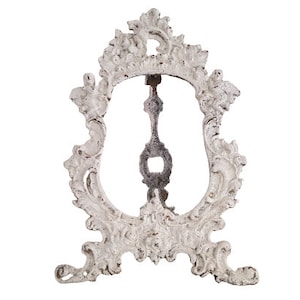 May include: White ornate metal picture frame with a decorative design. The frame is made of cast iron and has a distressed finish.