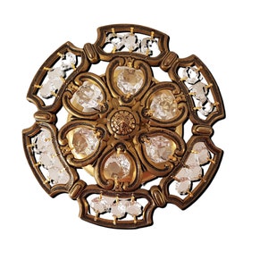 Peut inclure: Luminaire de plafond orné de style antique. Le luminaire présente un design circulaire avec un cadre en métal de couleur bronze. Des cristaux clairs et facettés sont sertis dans le cadre et au centre. La lumière a un motif floral.