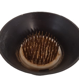 Vintage round metal flower frog in a plastic cup. Flower stand with spikes. Retro arranger.