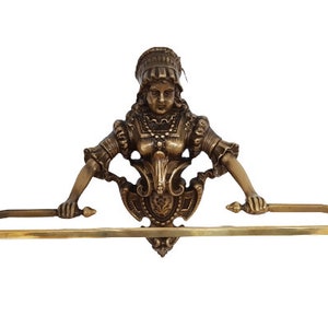 May include: A gold-toned metal towel rack with a decorative figure of a woman in a dress holding the ends of the rack. The woman's face is visible and she has a crown on her head.