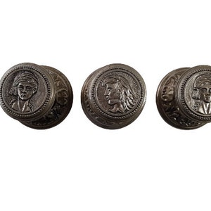 May include: Three silver-toned metal knobs with ornate designs and a profile of a person's face in the centre.