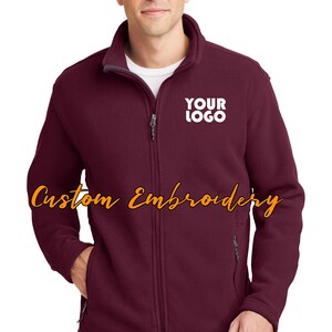 May include: Burgundy fleece zip-up jacket with a gray zipper and a white embroidered logo that says "YOUR LOGO".