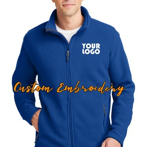 May include: A royal blue fleece jacket with a zipper closure and two front pockets. The jacket has a white embroidered logo that says "YOUR LOGO" on the left chest.