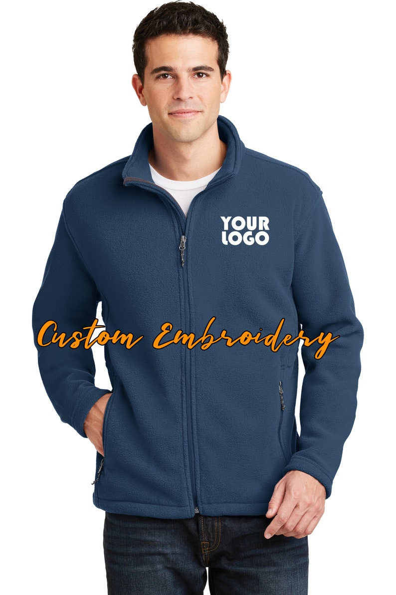 May include: A dark blue fleece jacket with a zipper closure and two front pockets. The jacket has a white embroidered logo that says "YOUR LOGO" on the left chest.