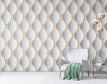 May include: A white chair with a green throw blanket sits in front of a wall with a white and gold geometric pattern. Three gold pendant lights hang from the ceiling.