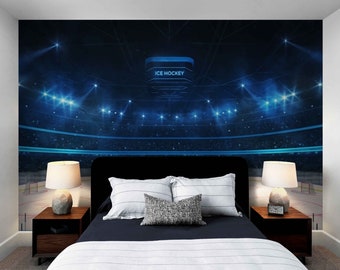 May include: A bedroom with a dark blue wall mural depicting an ice hockey arena with spotlights and the words "ICE HOCKEY" on a scoreboard. The room features a bed with a black headboard, white and gray striped bedding, and two lamps on nightstands.